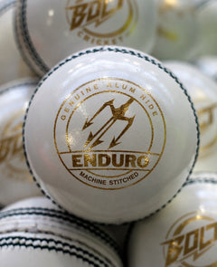 White Bolt Enduro cricket ball with gold Enduro Machine Stitched marking, among other white balls